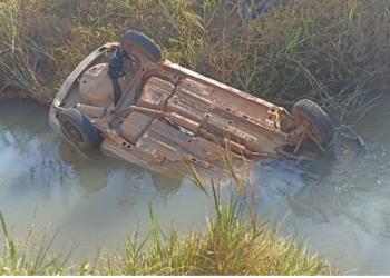 Filho percebe que carro dos pais estava demorando, voltou e viu o veículo com as rodas pro alto dentro de rio