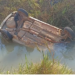 Filho percebe que carro dos pais estava demorando, voltou e viu o veículo com as rodas pro alto dentro de rio