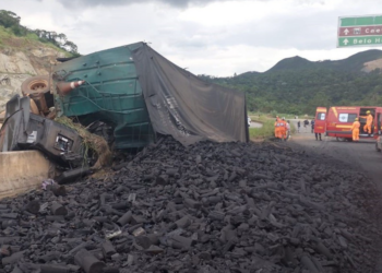 Carreta carregada de carvão tomba e fica pendurada em viaduto da BR-381, em Caeté